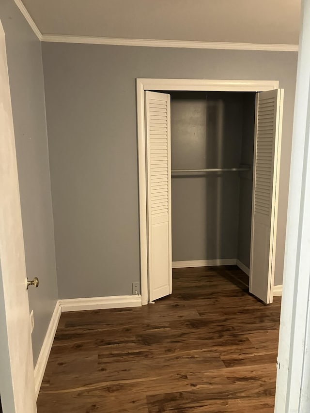 unfurnished bedroom with crown molding, dark hardwood / wood-style flooring, and a closet