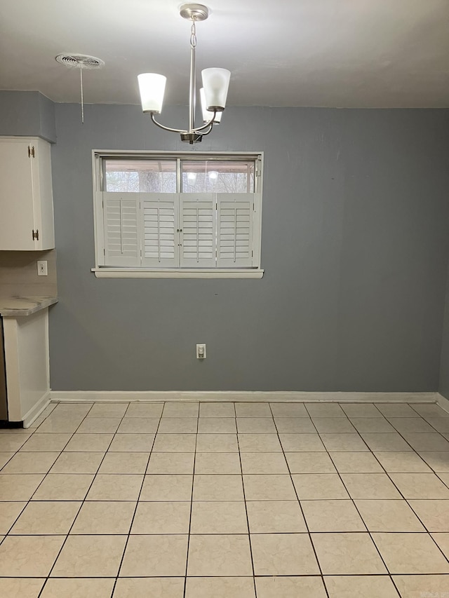 unfurnished dining area featuring light tile patterned floors and an inviting chandelier