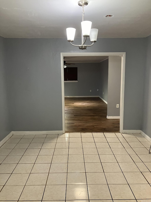 spare room featuring ceiling fan with notable chandelier and light tile patterned flooring