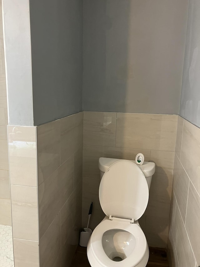 bathroom with tile walls and toilet