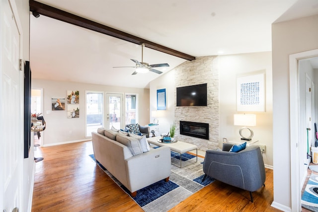 living room featuring a stone fireplace, vaulted ceiling with beams, hardwood / wood-style floors, and ceiling fan