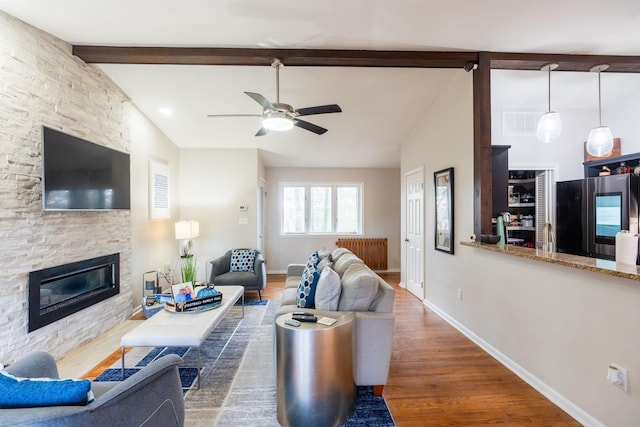 living room featuring ceiling fan, a fireplace, dark hardwood / wood-style flooring, and lofted ceiling with beams