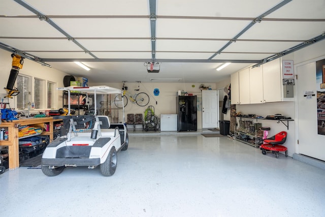 garage featuring a garage door opener, fridge, and black fridge