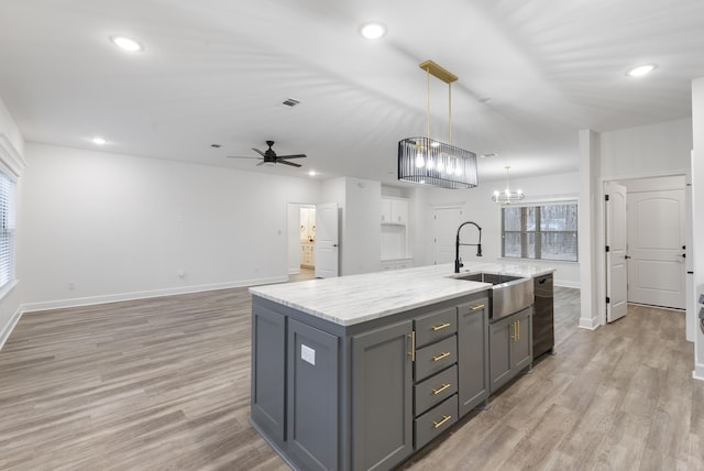 kitchen featuring gray cabinets, decorative light fixtures, an island with sink, sink, and light hardwood / wood-style floors