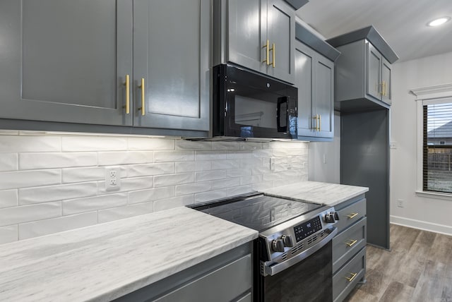 kitchen featuring electric stove, gray cabinets, light stone countertops, dark hardwood / wood-style flooring, and decorative backsplash