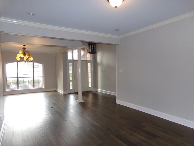 spare room with decorative columns, crown molding, dark hardwood / wood-style floors, and a notable chandelier