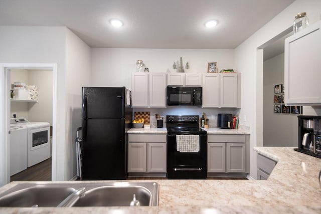 kitchen featuring sink, gray cabinetry, washing machine and clothes dryer, and black appliances