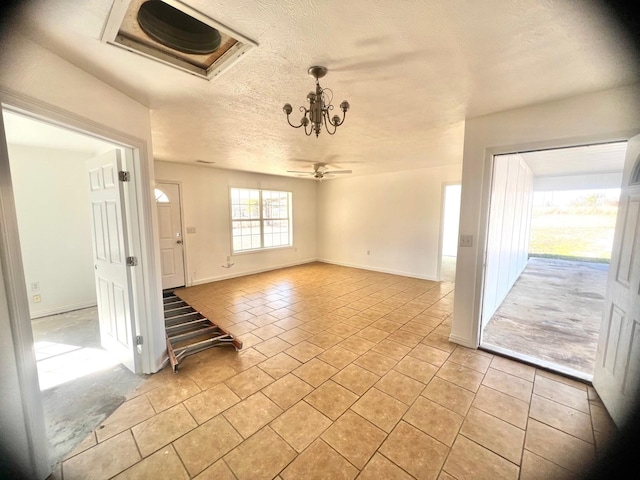 tiled spare room with ceiling fan with notable chandelier and a textured ceiling