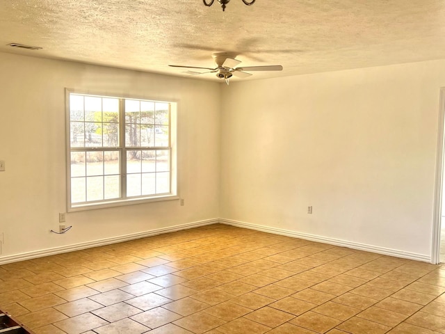 spare room featuring ceiling fan, a textured ceiling, and light tile patterned floors