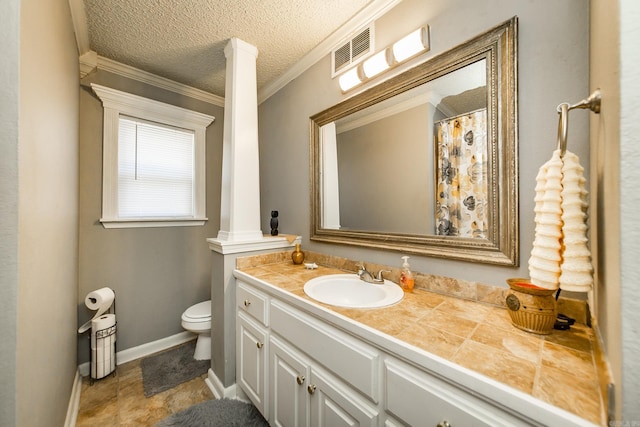 bathroom with toilet, a textured ceiling, ornamental molding, vanity, and decorative columns