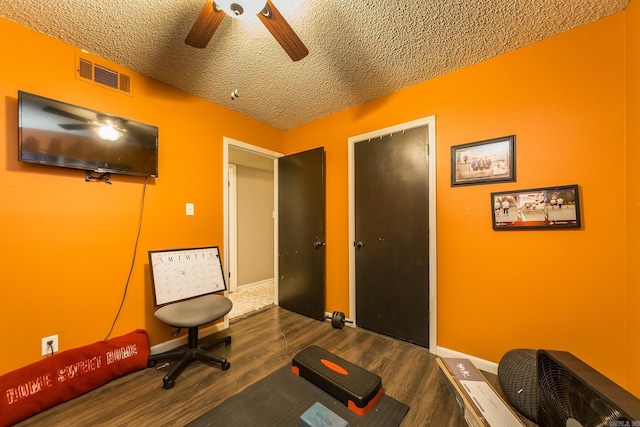 exercise room with wood-type flooring, ceiling fan, and a textured ceiling