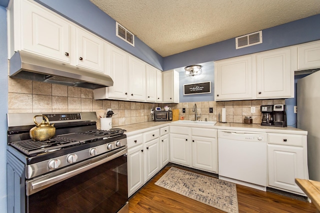 kitchen with stainless steel gas range, sink, white cabinetry, dark hardwood / wood-style flooring, and white dishwasher