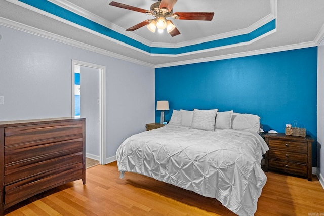 bedroom featuring hardwood / wood-style floors, ornamental molding, and a raised ceiling