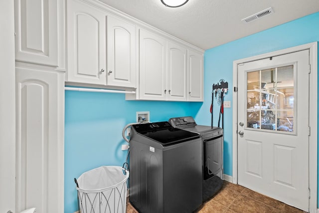 clothes washing area featuring independent washer and dryer, cabinets, a textured ceiling, and dark tile patterned flooring