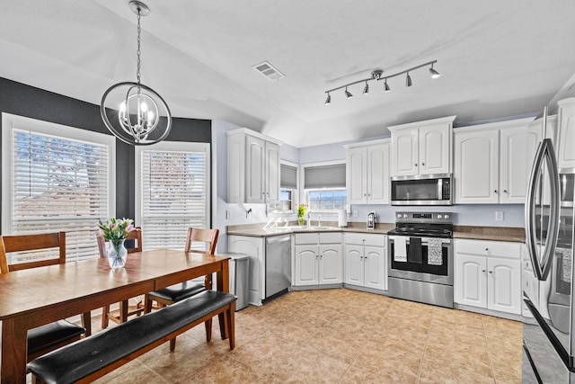 kitchen with hanging light fixtures, white cabinetry, appliances with stainless steel finishes, and an inviting chandelier