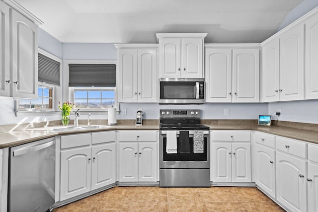 kitchen featuring sink, light tile patterned floors, stainless steel appliances, and white cabinets