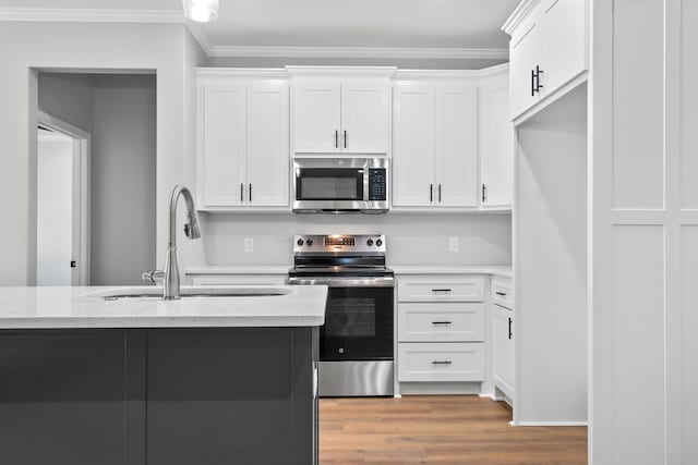 kitchen with light stone counters, stainless steel appliances, light hardwood / wood-style flooring, and white cabinets