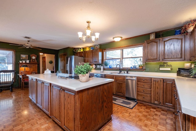 kitchen with a kitchen island, decorative light fixtures, sink, stainless steel appliances, and a textured ceiling