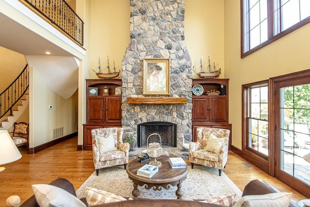 living room featuring a stone fireplace, a wealth of natural light, and light hardwood / wood-style flooring