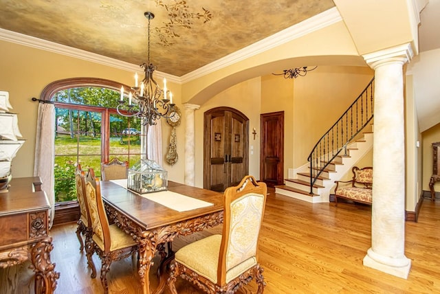 dining area featuring an inviting chandelier, ornamental molding, light hardwood / wood-style flooring, and ornate columns