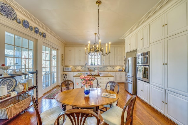 dining room with crown molding, a notable chandelier, and light hardwood / wood-style floors