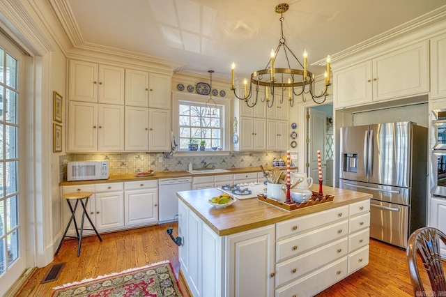 kitchen featuring light hardwood / wood-style flooring, butcher block counters, hanging light fixtures, stainless steel appliances, and a kitchen island