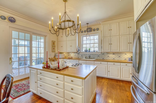 kitchen with decorative light fixtures, light wood-type flooring, stainless steel refrigerator, and a center island