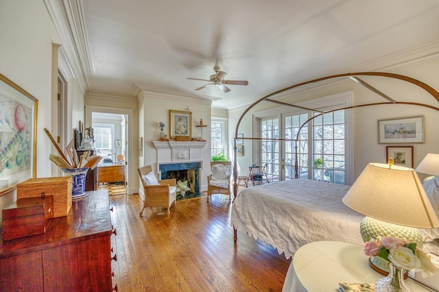 bedroom with hardwood / wood-style flooring, crown molding, and a high end fireplace