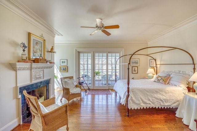 bedroom with hardwood / wood-style flooring, crown molding, access to outside, and a high end fireplace