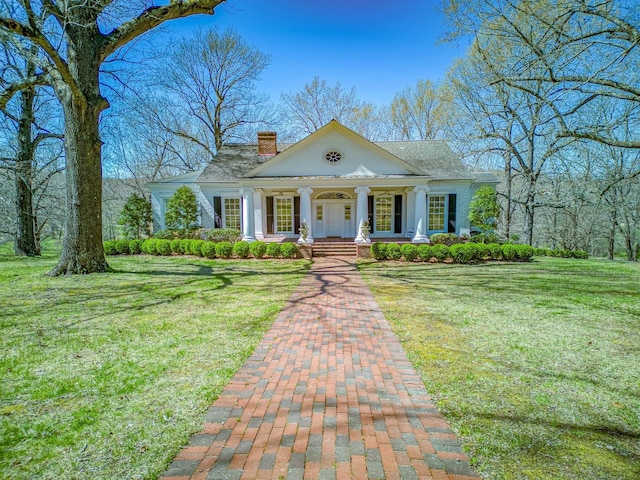 greek revival inspired property with covered porch and a front yard