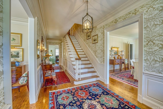 foyer featuring crown molding, an inviting chandelier, and hardwood / wood-style floors