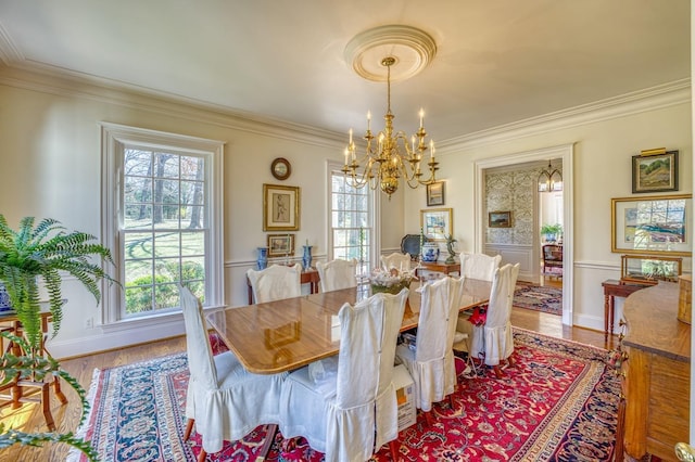 dining area featuring ornamental molding, wood-type flooring, a wealth of natural light, and an inviting chandelier