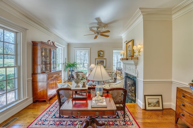 dining space with light hardwood / wood-style flooring, ornamental molding, and a healthy amount of sunlight