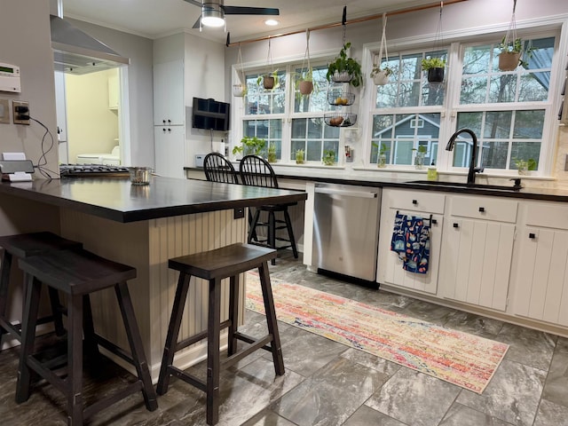 kitchen with a kitchen bar, sink, white cabinetry, hanging light fixtures, and stainless steel dishwasher