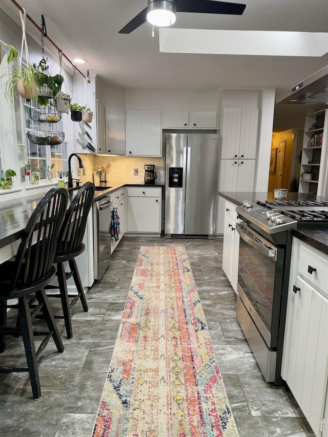 kitchen featuring appliances with stainless steel finishes, tasteful backsplash, white cabinetry, ceiling fan, and a textured ceiling