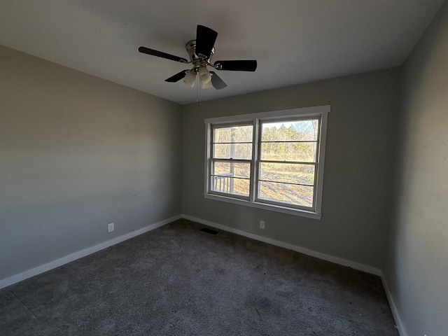 unfurnished room with ceiling fan and dark colored carpet