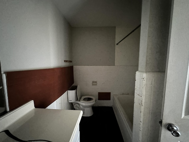 bathroom featuring a bathing tub, tile walls, and toilet