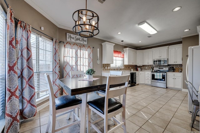 kitchen featuring tasteful backsplash, decorative light fixtures, ornamental molding, appliances with stainless steel finishes, and white cabinets