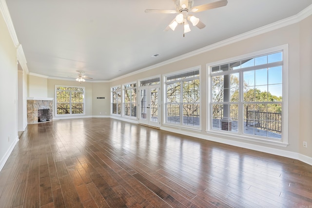 unfurnished living room featuring dark wood-type flooring, ornamental molding, and a stone fireplace