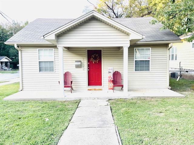 bungalow-style house with cooling unit and a front lawn