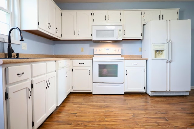 kitchen featuring hardwood / wood-style flooring, sink, white cabinets, and white appliances