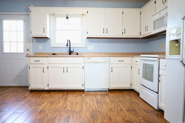 kitchen with hardwood / wood-style flooring, white cabinetry, sink, and white appliances