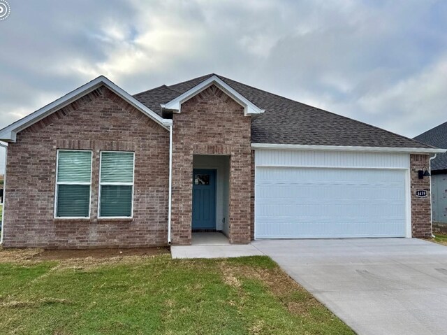 ranch-style home with brick siding, a front lawn, concrete driveway, roof with shingles, and a garage