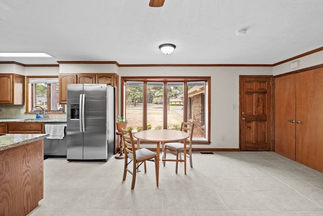 kitchen with sink, backsplash, ornamental molding, stainless steel appliances, and light stone countertops