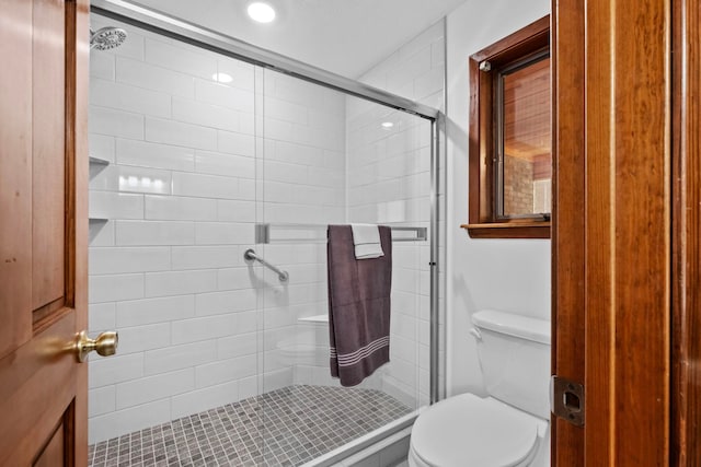 bathroom with toilet and a shower with shower door