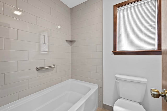 bathroom featuring tiled shower / bath combo and toilet