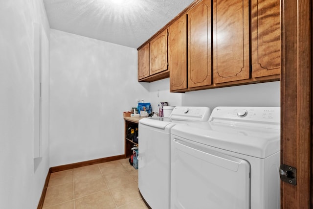 laundry area with cabinets, light tile patterned flooring, washing machine and clothes dryer, and a textured ceiling