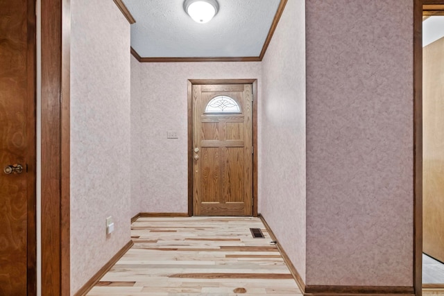 doorway to outside with crown molding, a textured ceiling, and light wood-type flooring