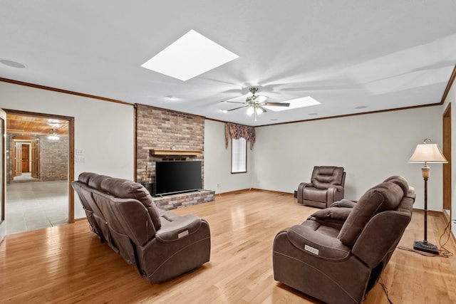 living room with crown molding, ceiling fan, a skylight, and light hardwood / wood-style floors