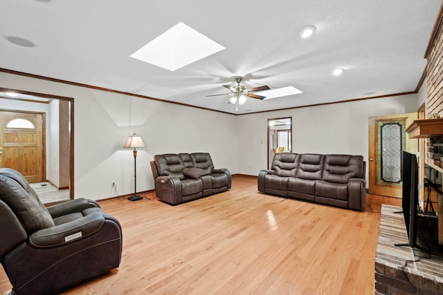 living room with ornamental molding, a brick fireplace, hardwood / wood-style floors, and a skylight